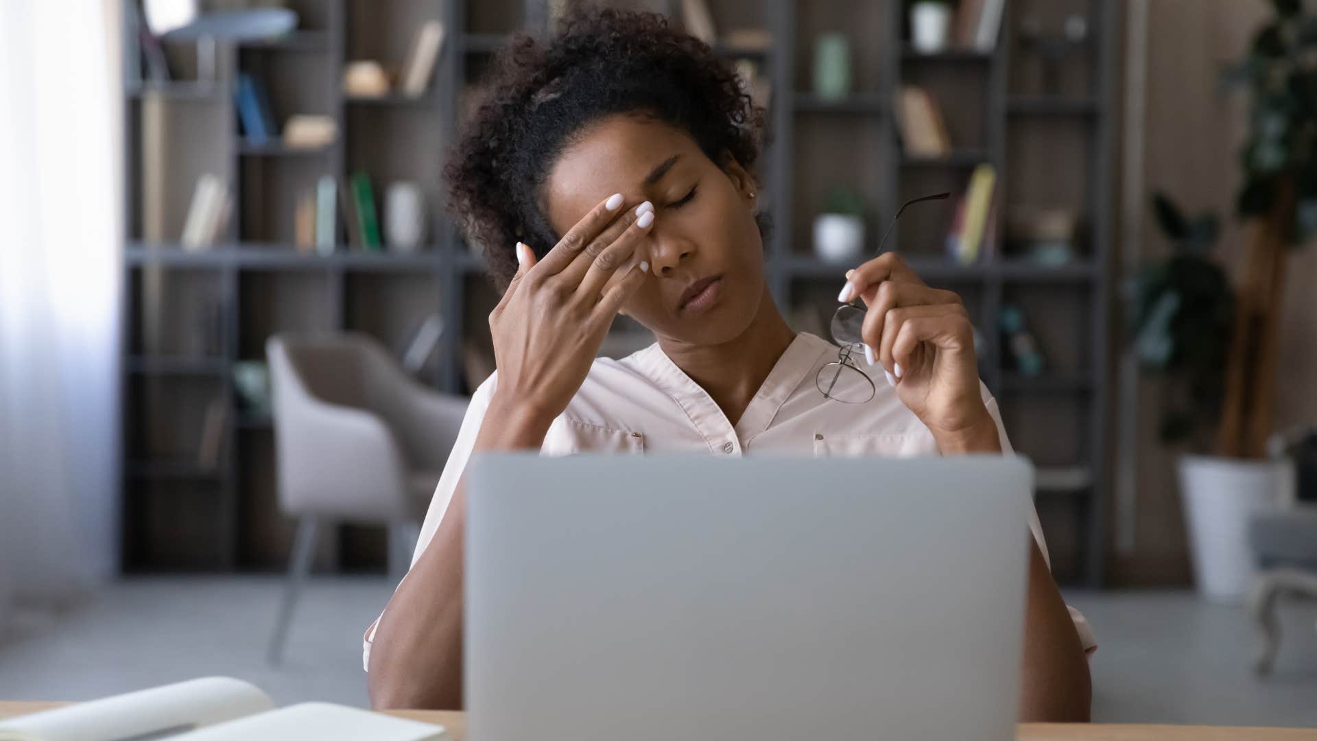 Woman looking stressed holding her head at work.