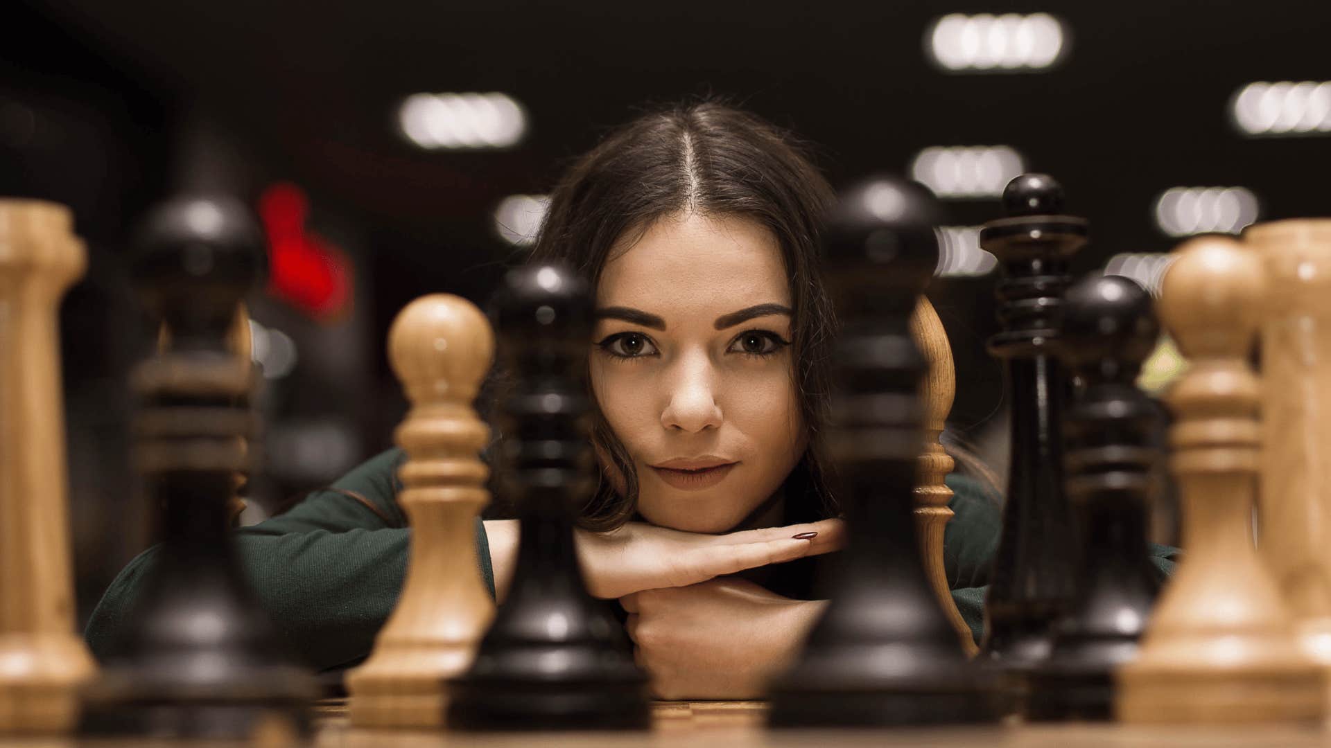 Woman looks through chess peices