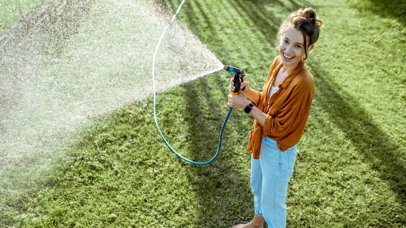 Woman watering a yard of weeds after her HOA complained 