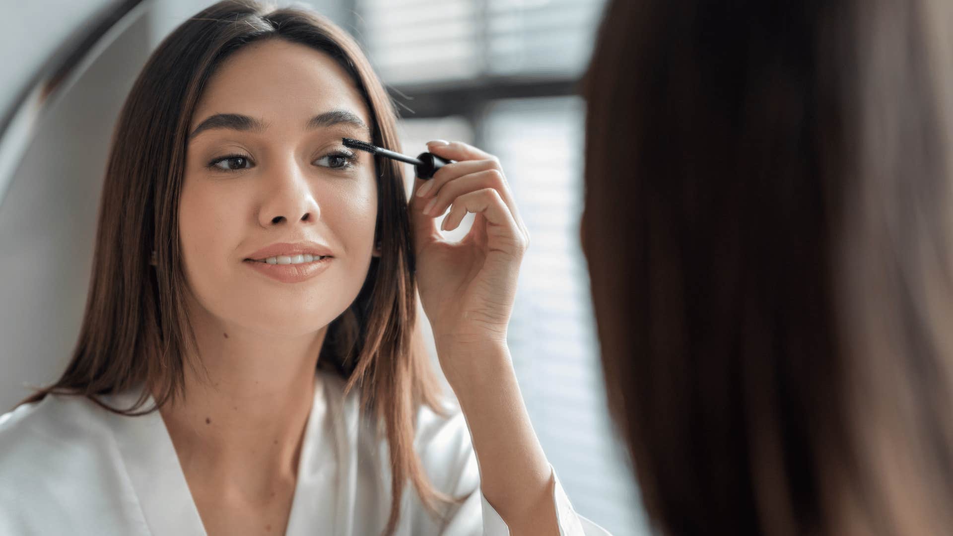 woman putting on makeup in mirror