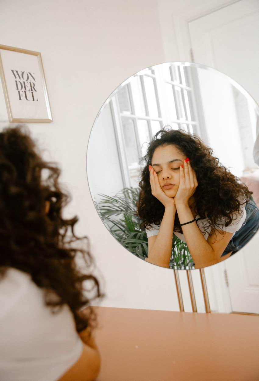 Woman struggling with her appearance while looking in mirror