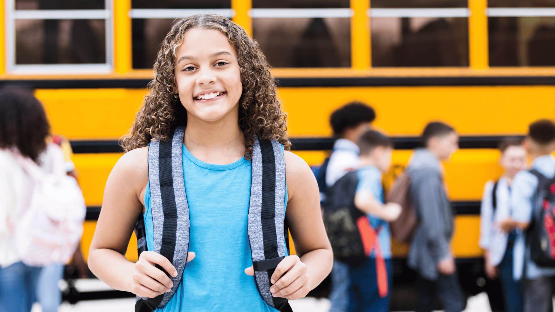 confident girl standing in front of school bus