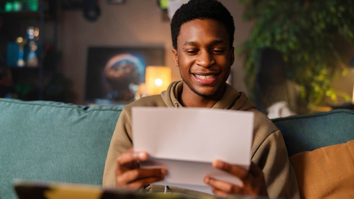 Man smiling and reading a handwritten letter