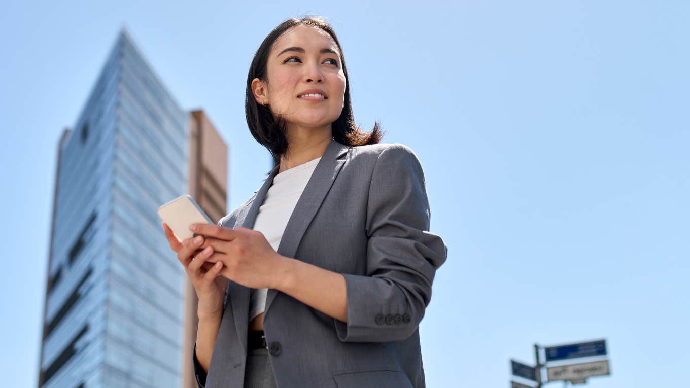 Woman looking away from her phone while walking in a city