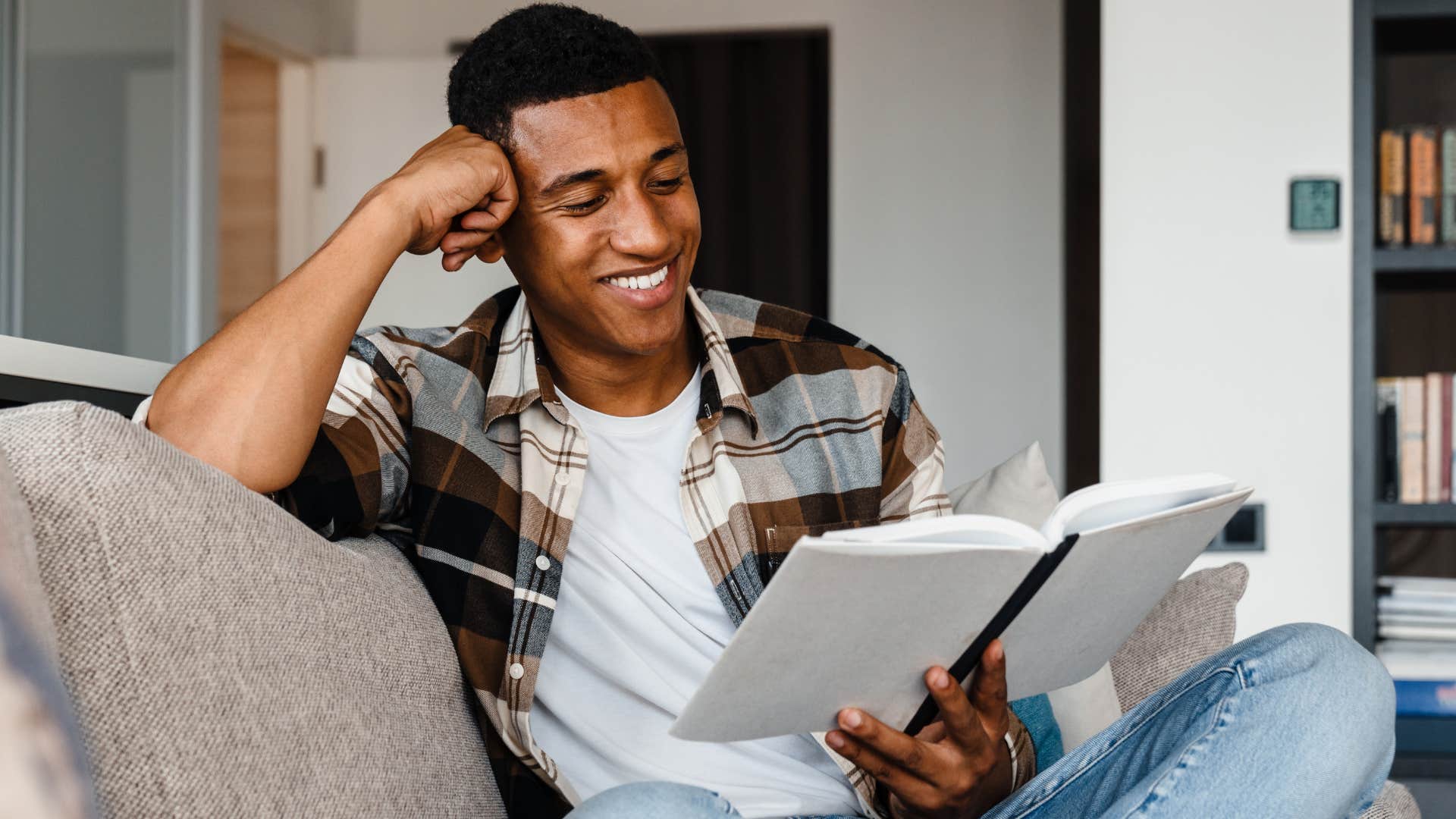 Man smiling and re-reading a childhood book on his couch