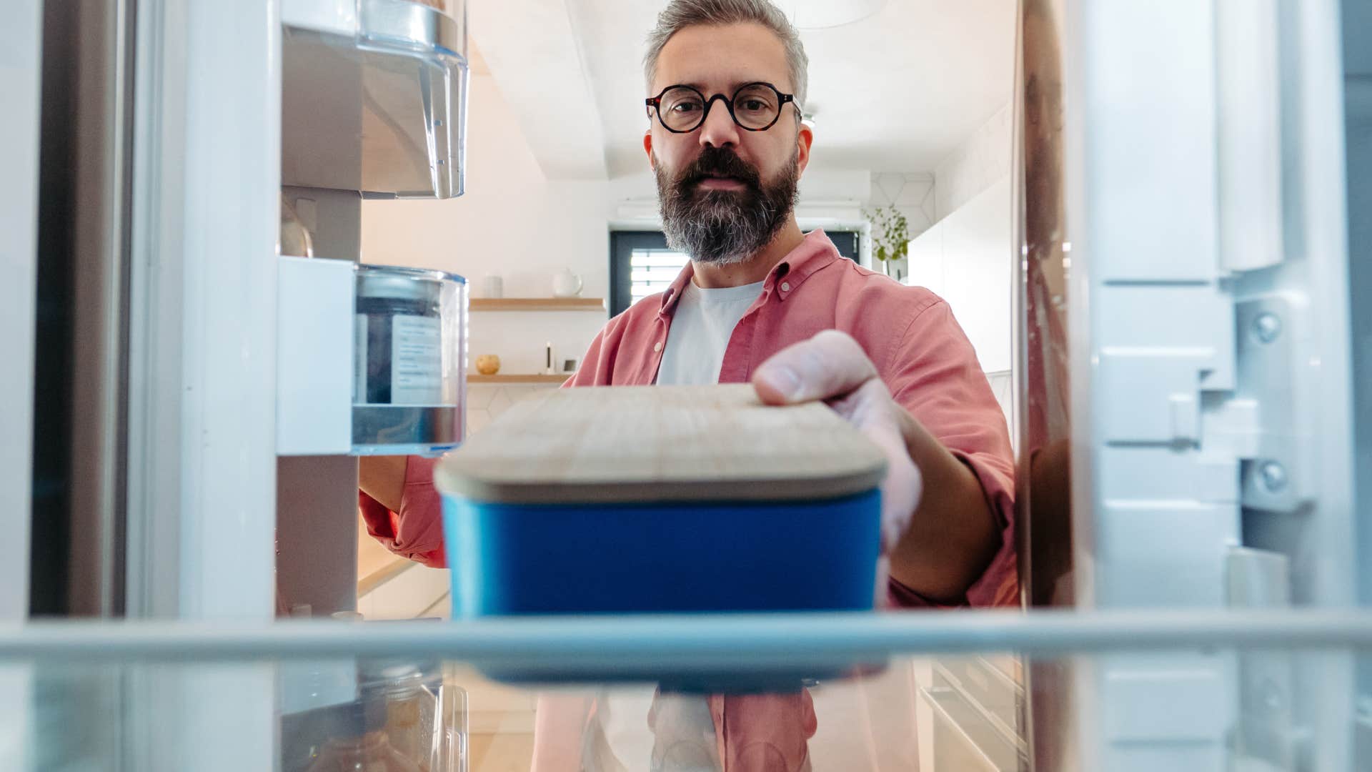 man putting reusable container in the fridge