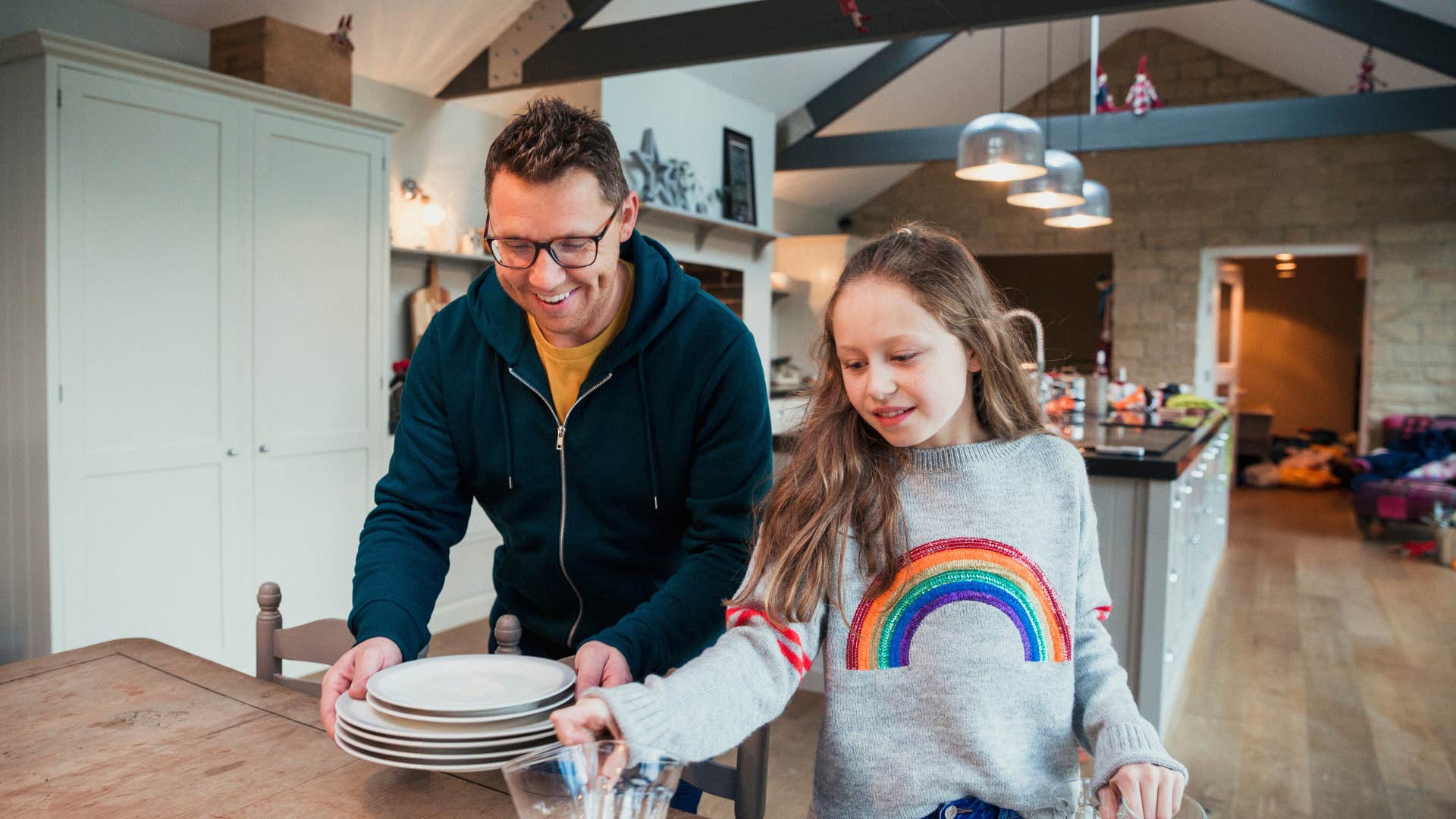 man setting dishes on table with daughter