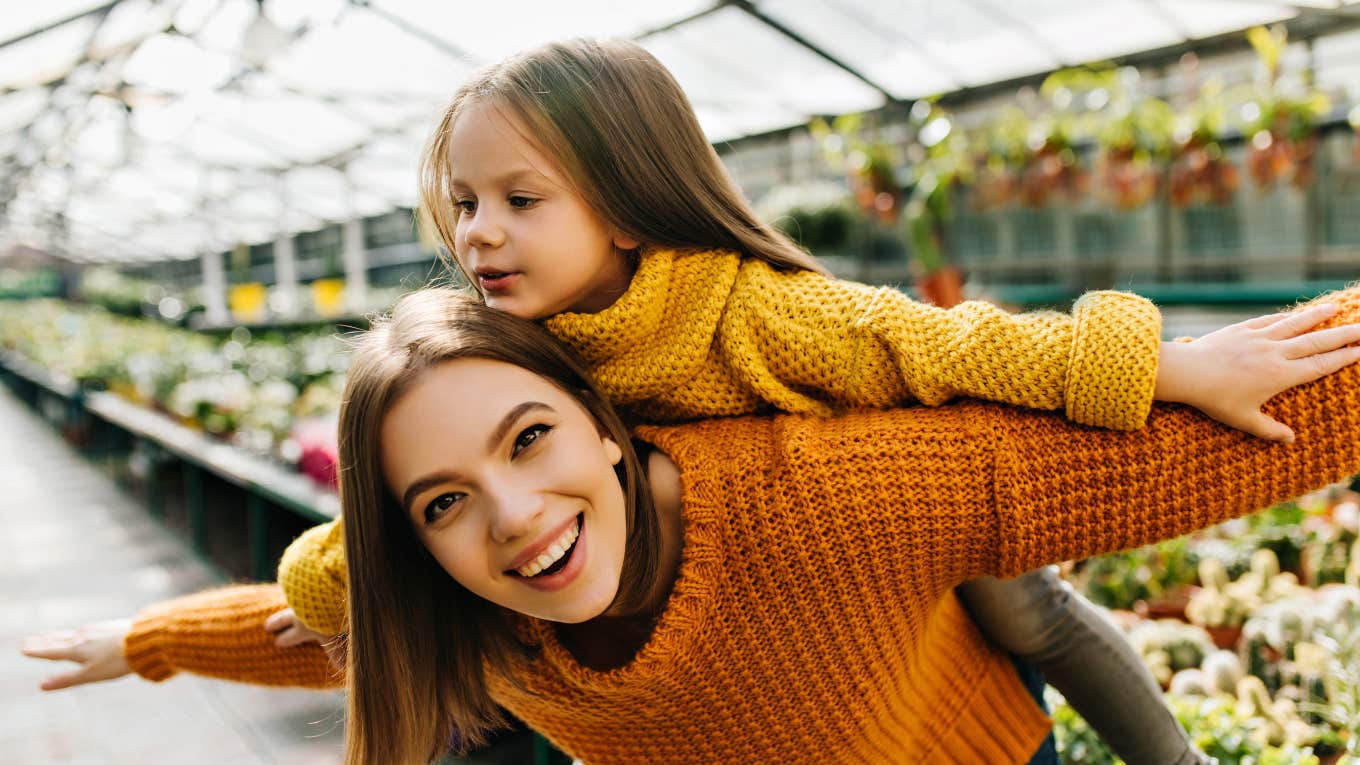 Laughing emotional woman posing in greenhouse with kid