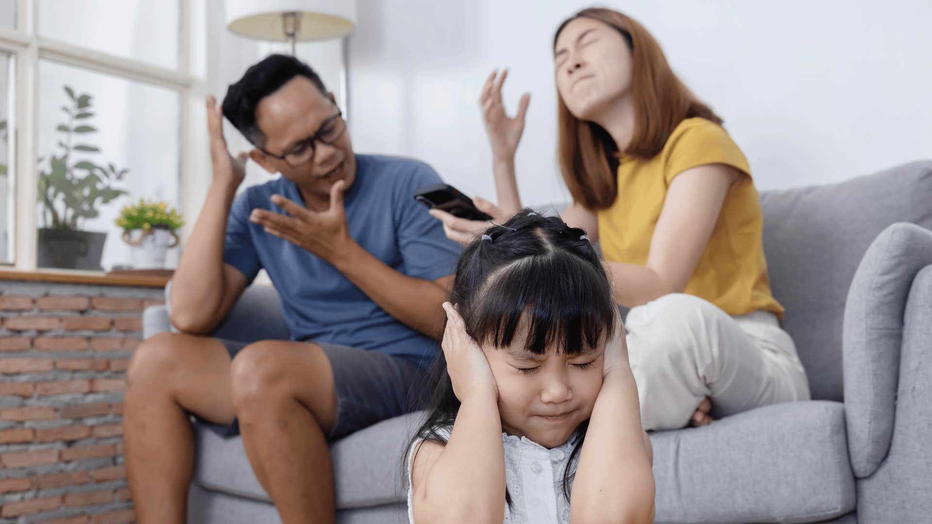 Couple argues while child covers ears