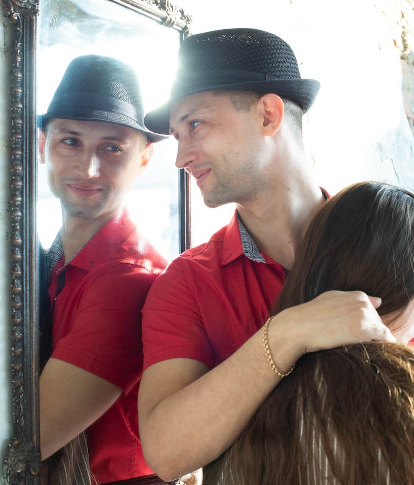 Self centered man looks at himself in a mirror and smiles