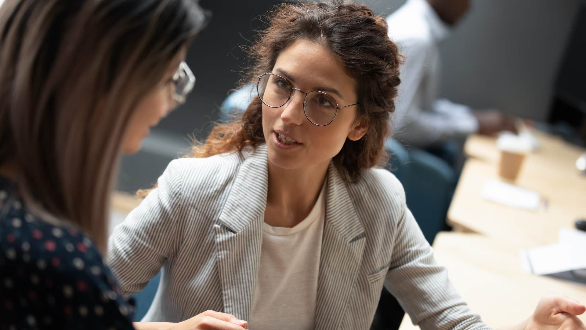 professional woman talking to a peer at her desk