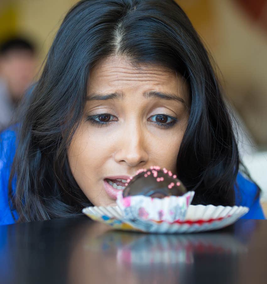 Playful woman looks at chocolate truffle