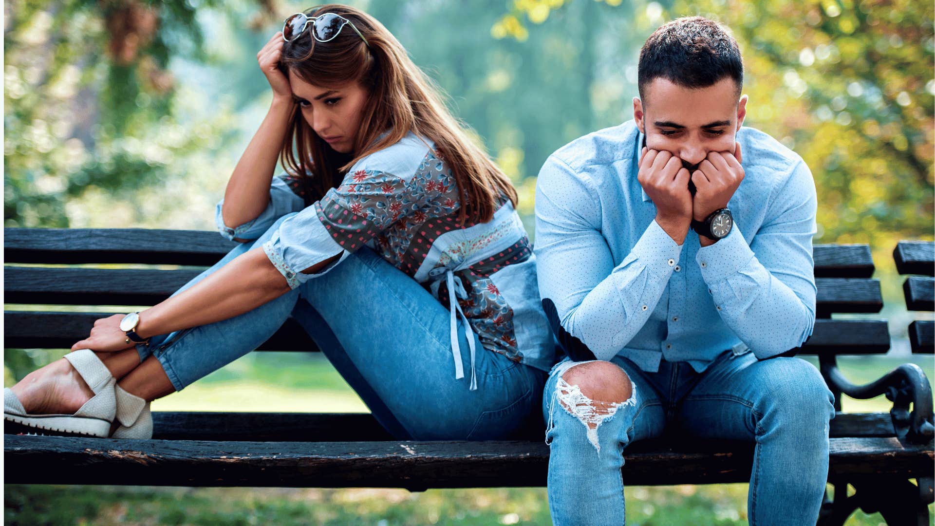 Couple feels tested by relationship while sitting uncomfortably on park bench