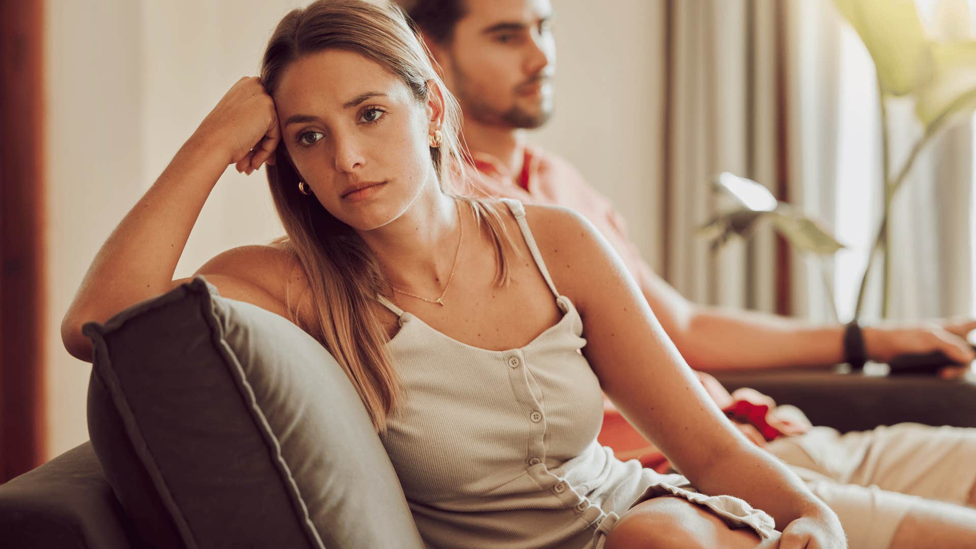 unhappy wife sitting next to man on couch