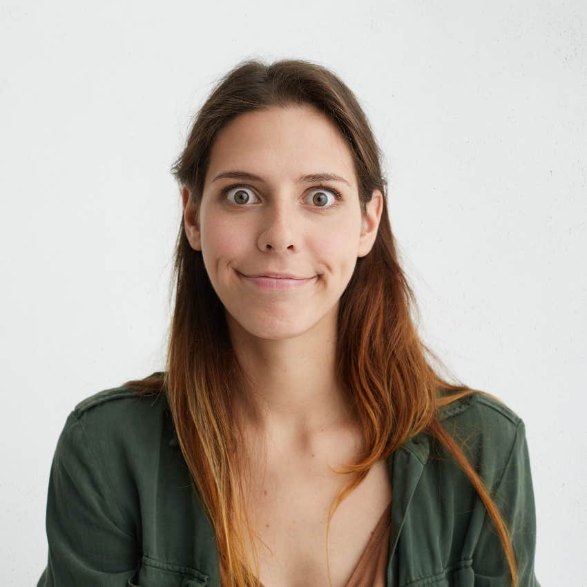 woman in green shirt compressing her lips with wide eyes