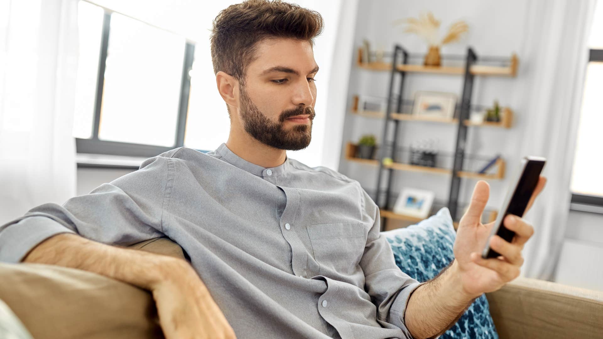 man staring at phone on couch