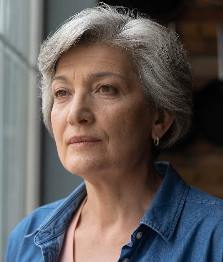 Older woman looks out window thoughtfully