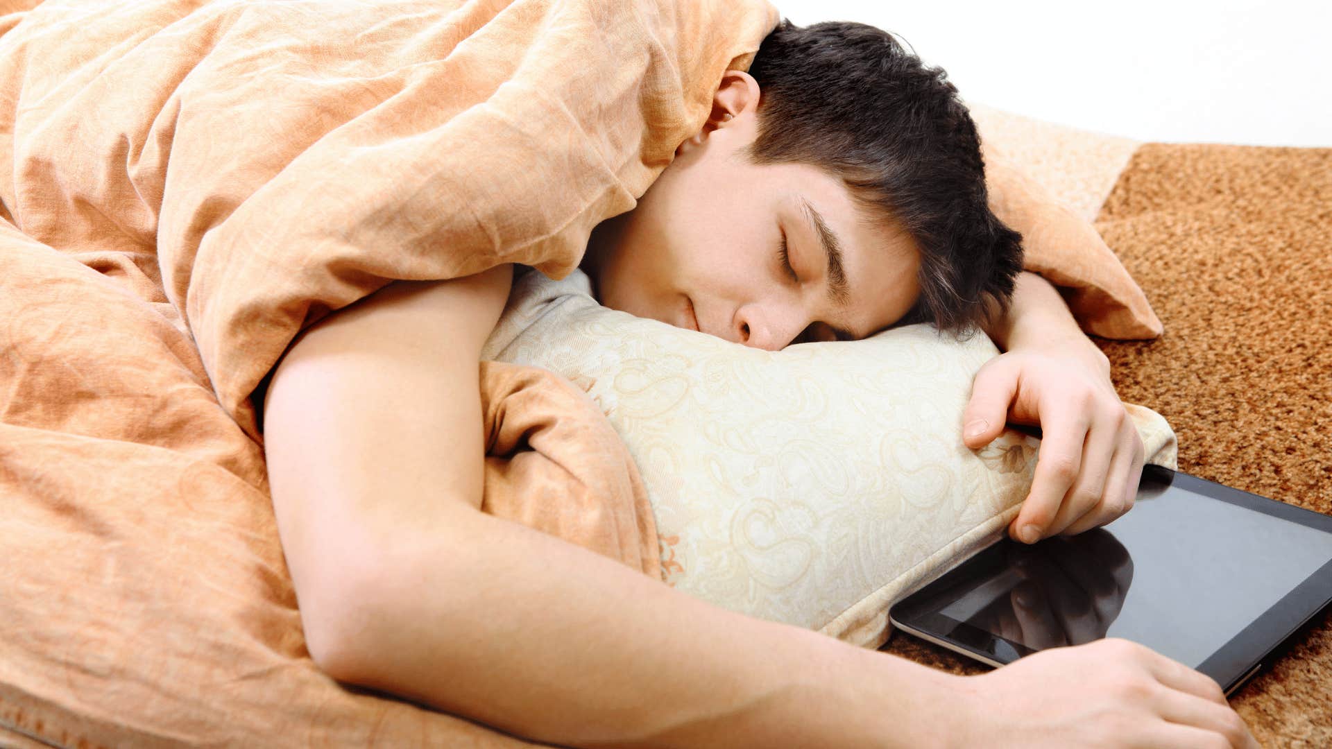 teenager sleeping next to tablet