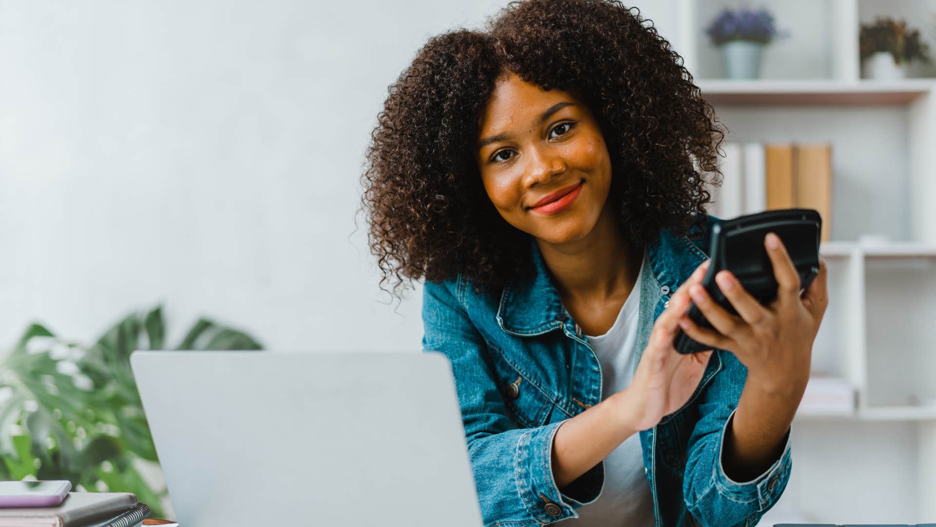 Gen Z woman smiling while doing bills on her computer