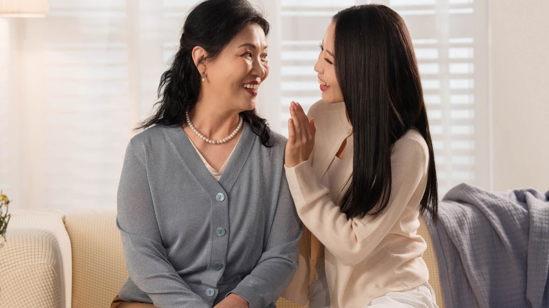 Gen Z woman hugging her mother on a couch