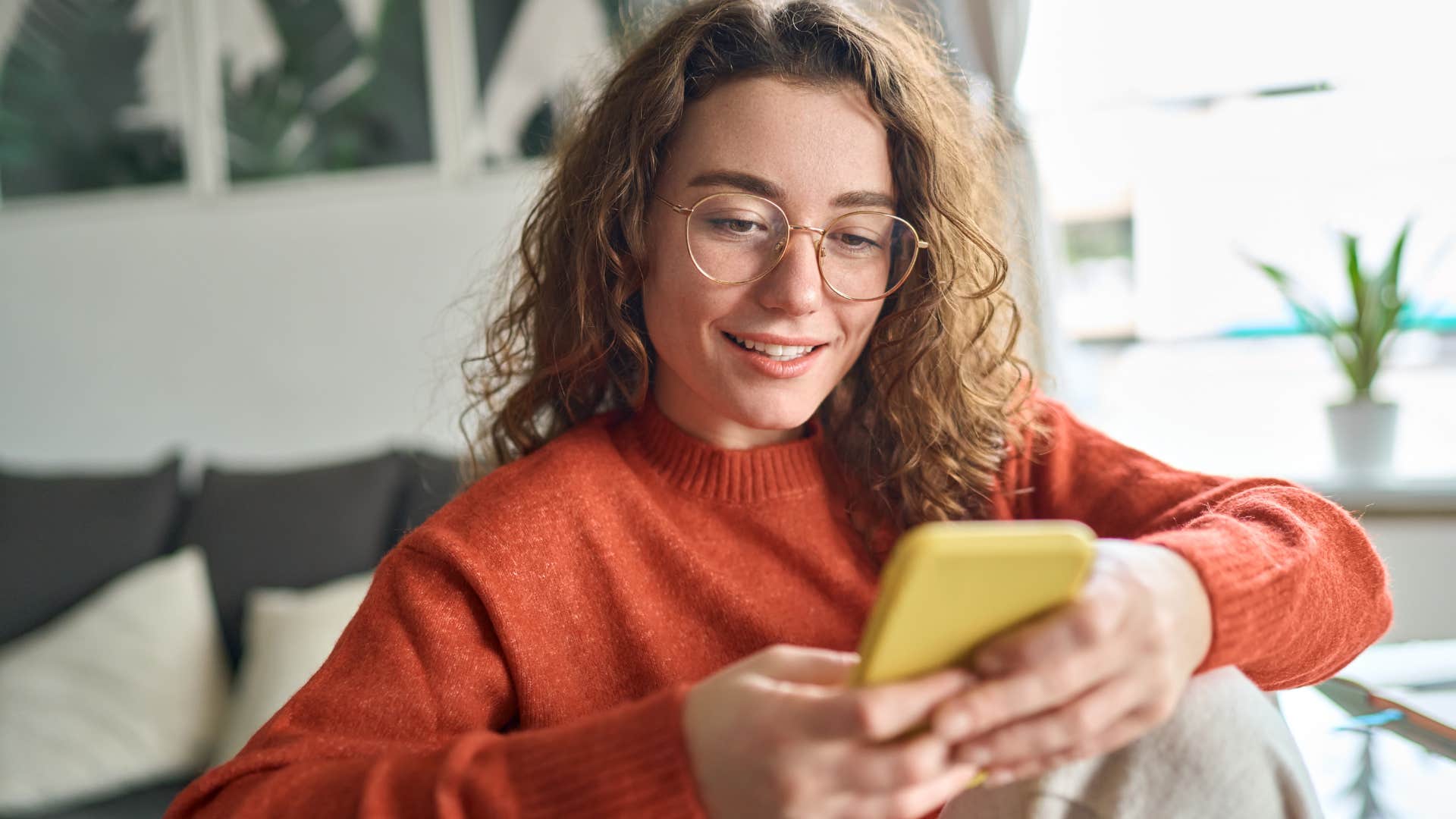 Gen Z woman smiling and scrolling on her phone