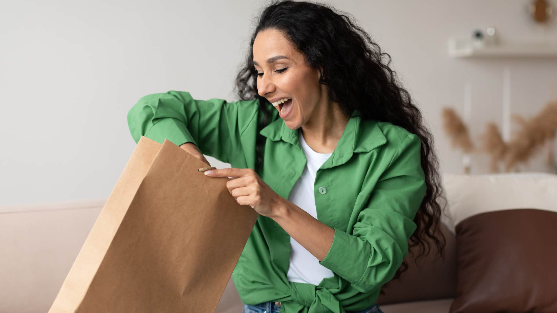 Gen Z woman smiling and looking in a paper bag