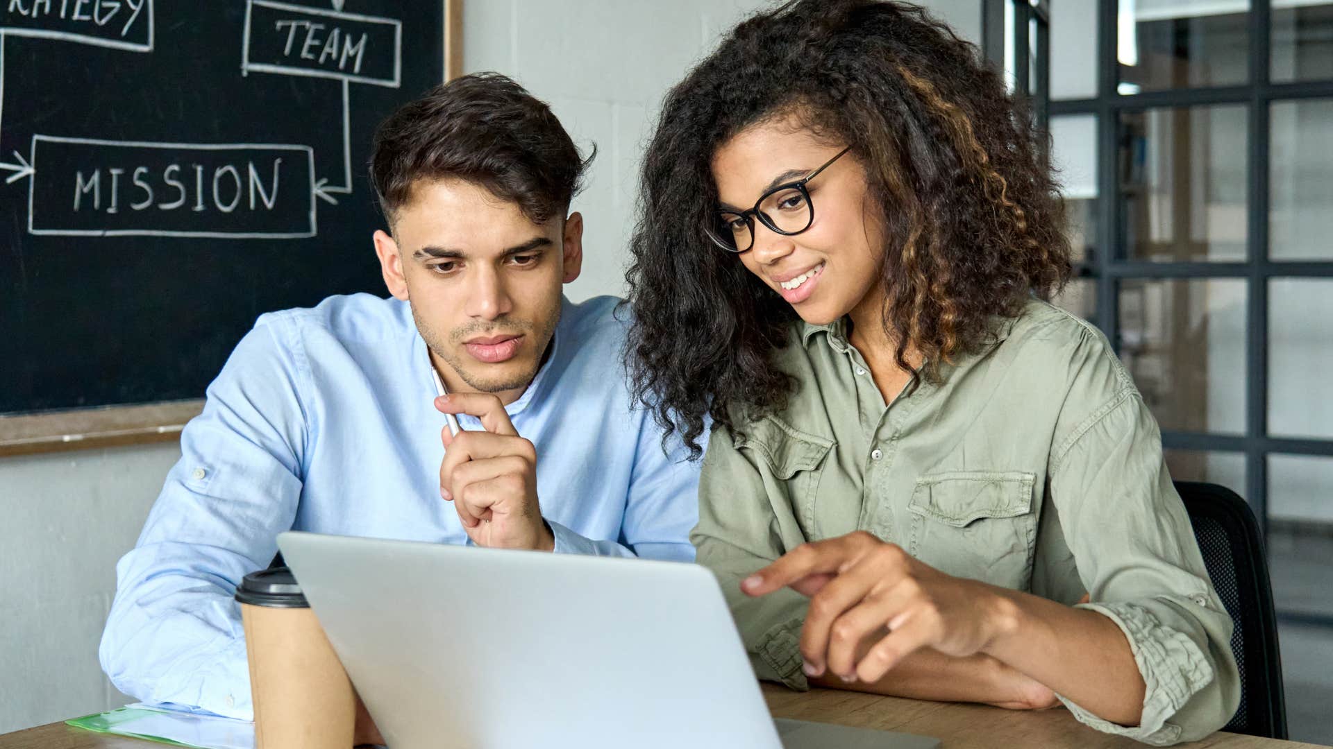 Gen Z couple smiling and looking at a computer