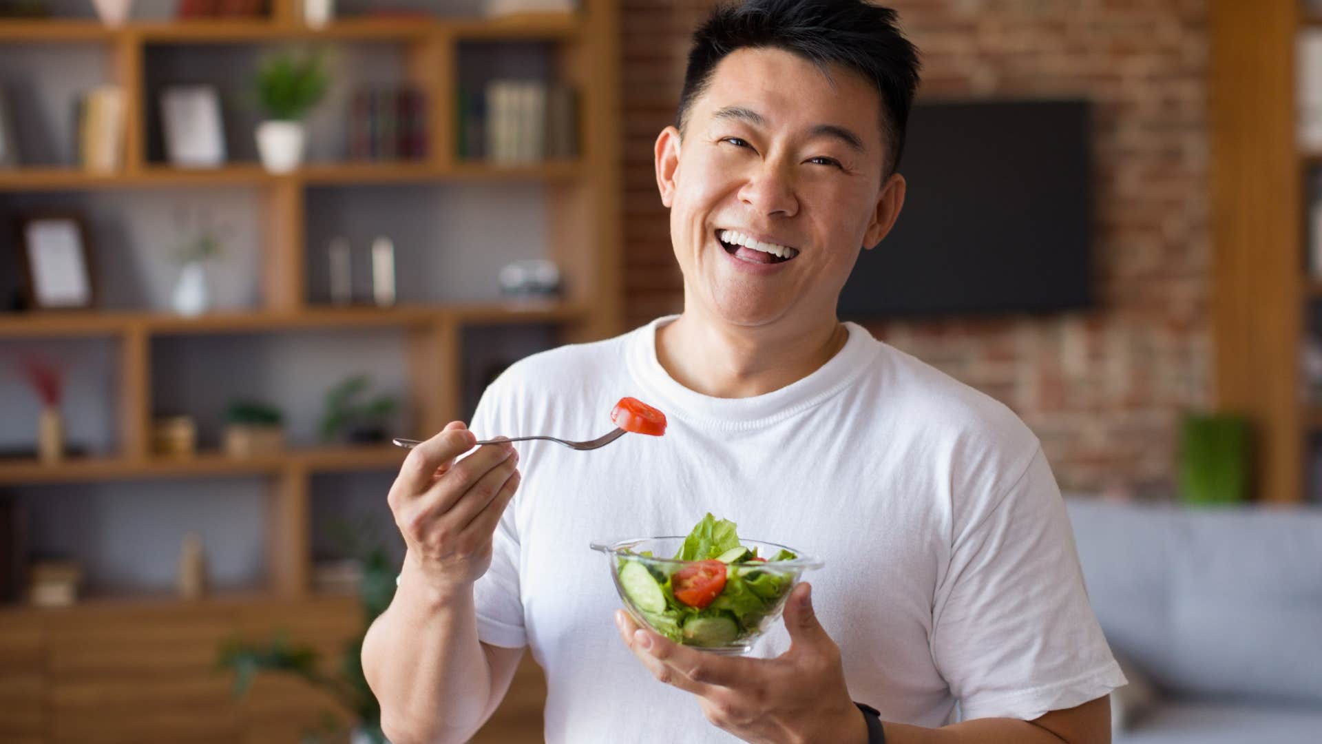 Gen Z man smiling and eating a salad