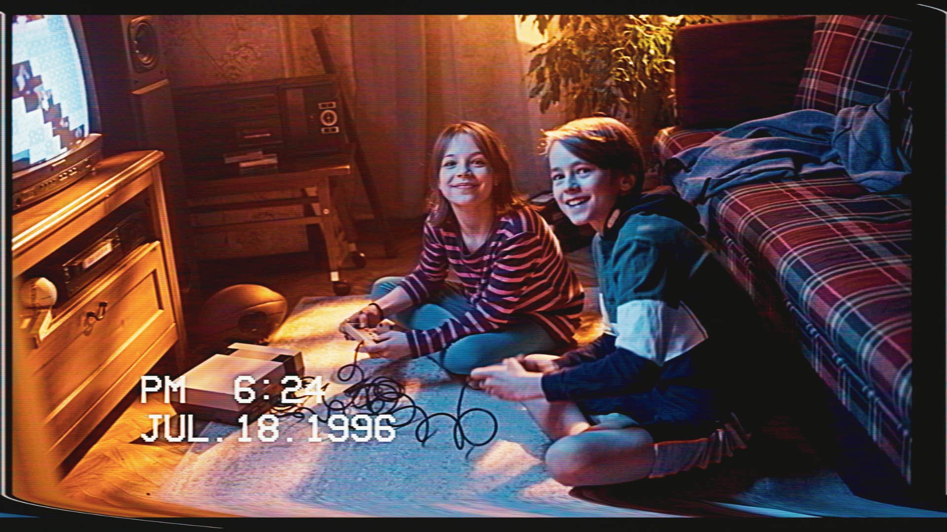 Old camcorder freeze frame of two teens playing retro video game