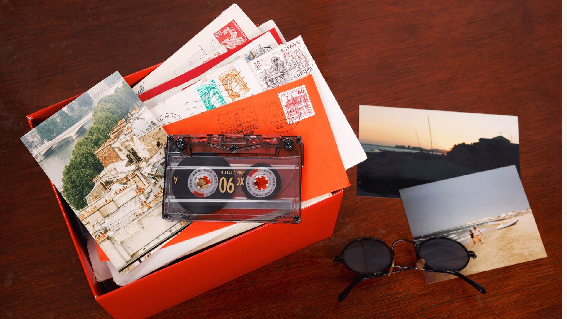 Open box containing a cassette tape, letters, post cards, and sun glasses