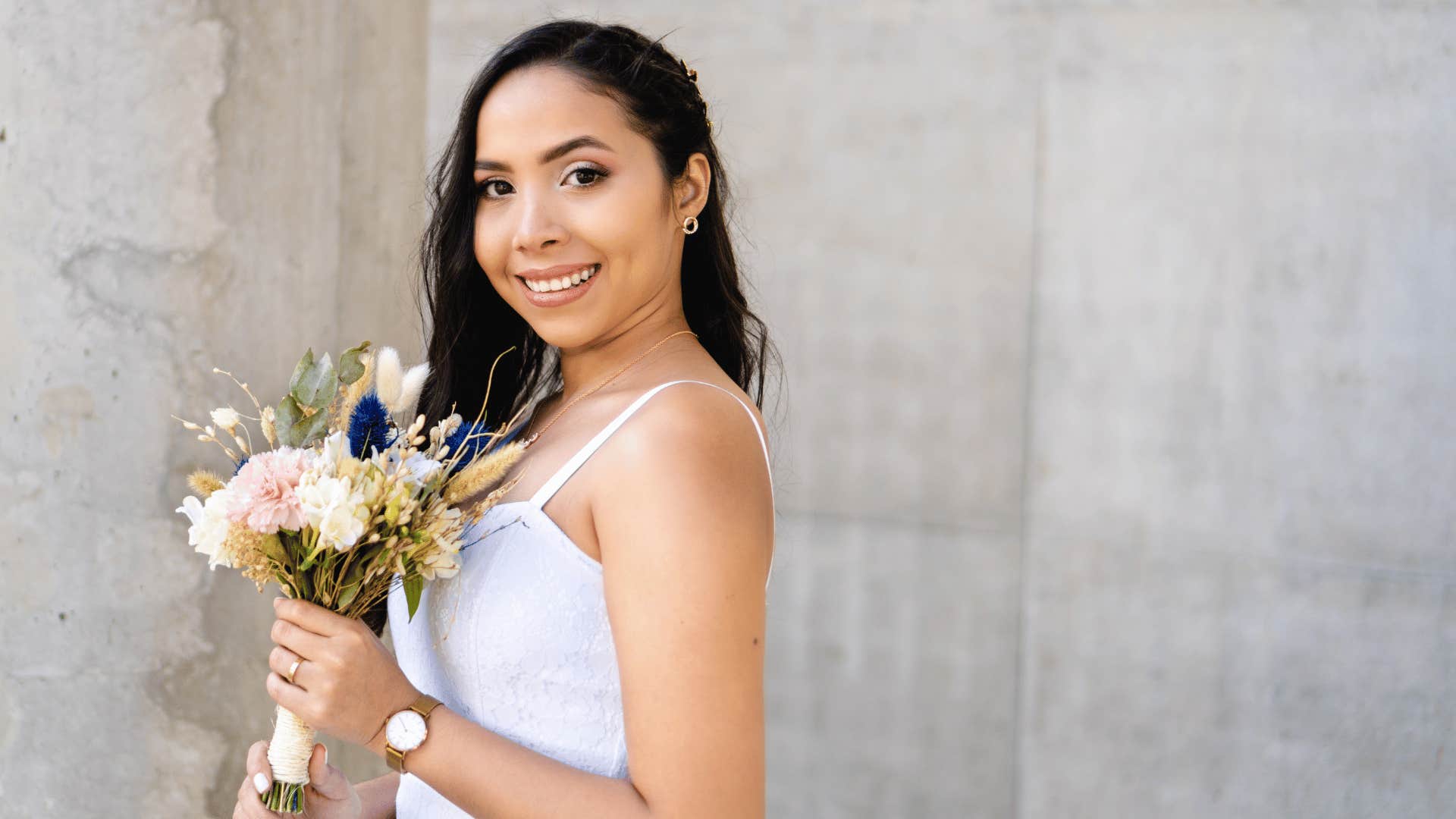 Smiling bride with flowers takes a moment to herself