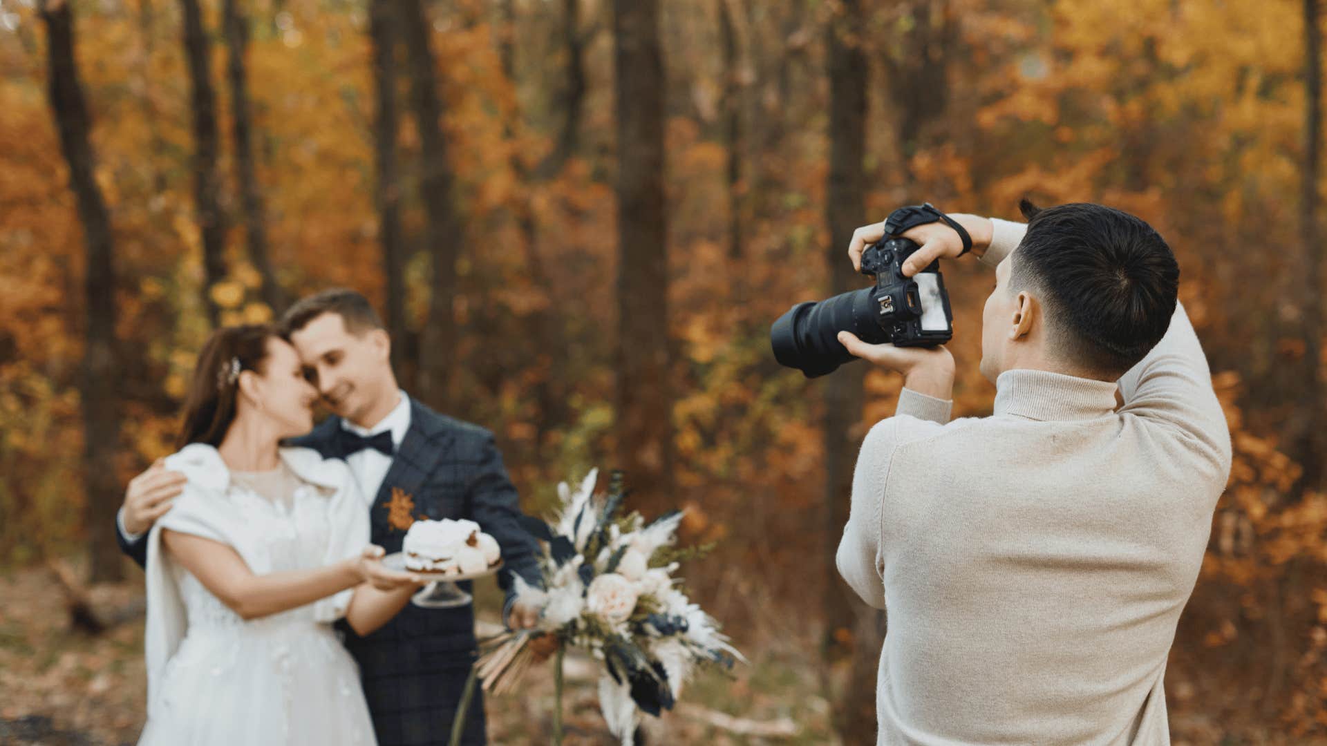 Professional photographer takes photos of bride and groom in autumn woods