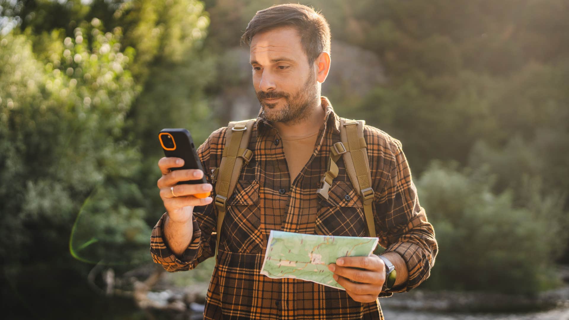 Gen Z man looking at his phone instead of a reading physical map