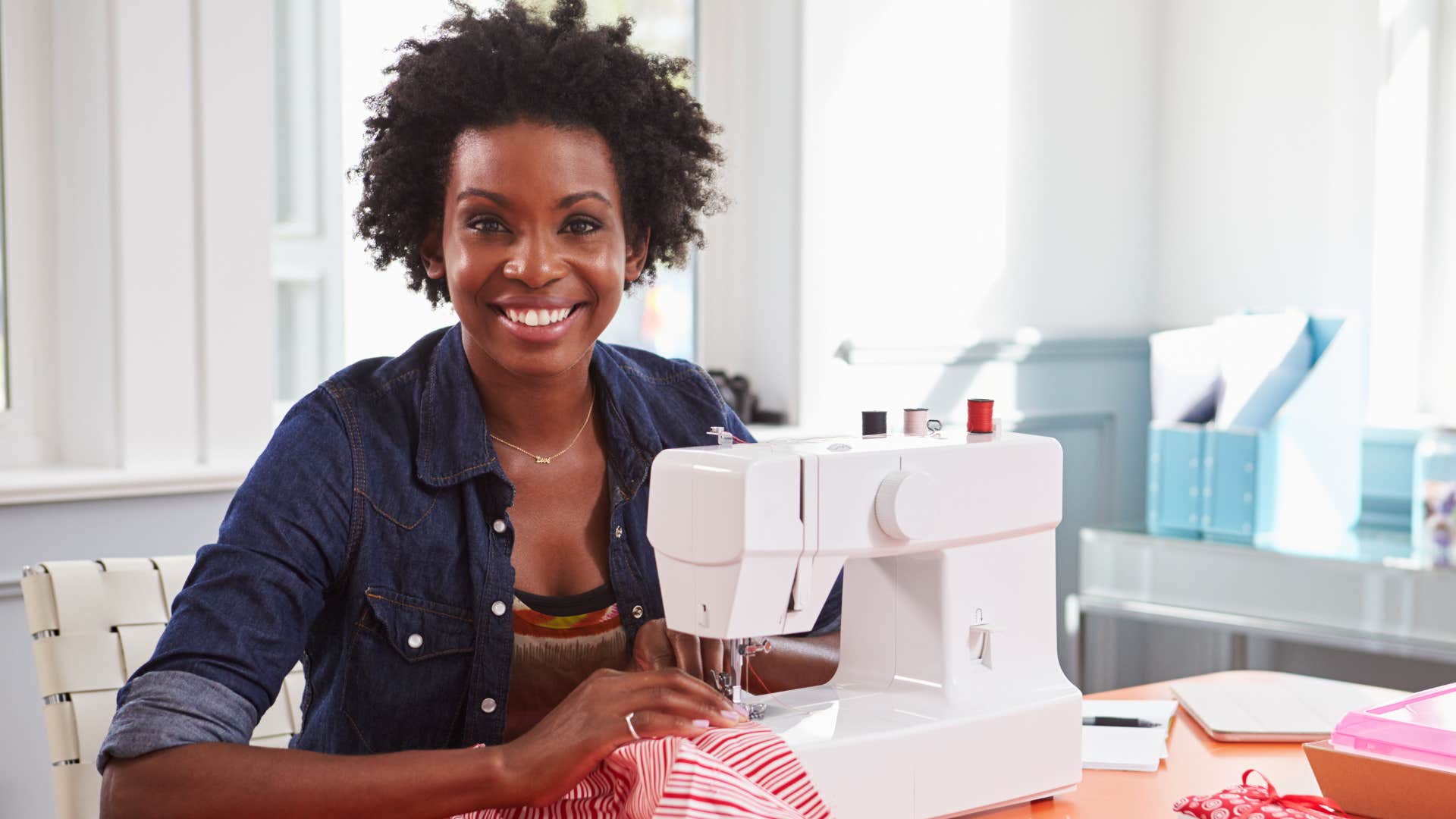 Young woman smiling next to a sewing machine