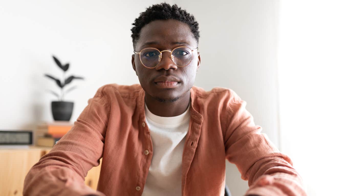 serious young man sitting in home looking at camera