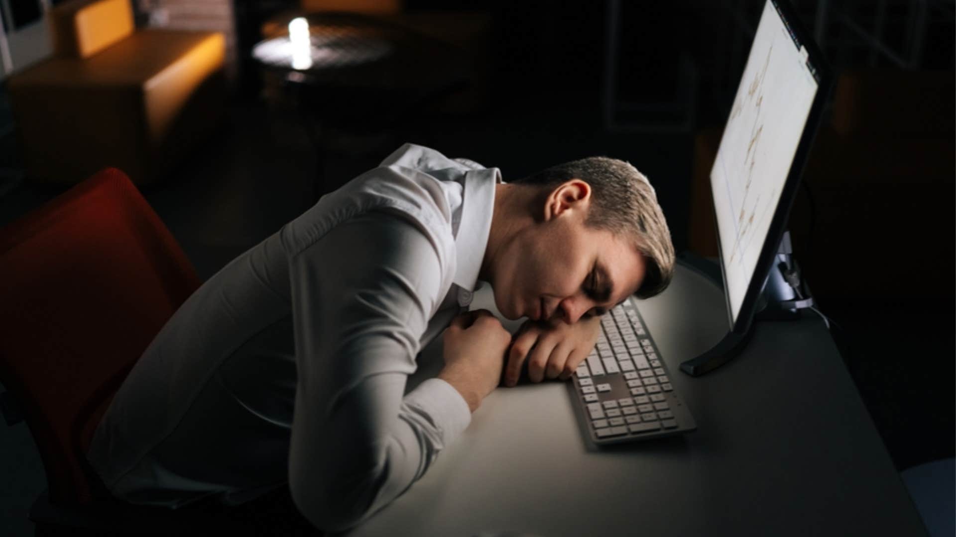 millennial man asleep while working overtime 