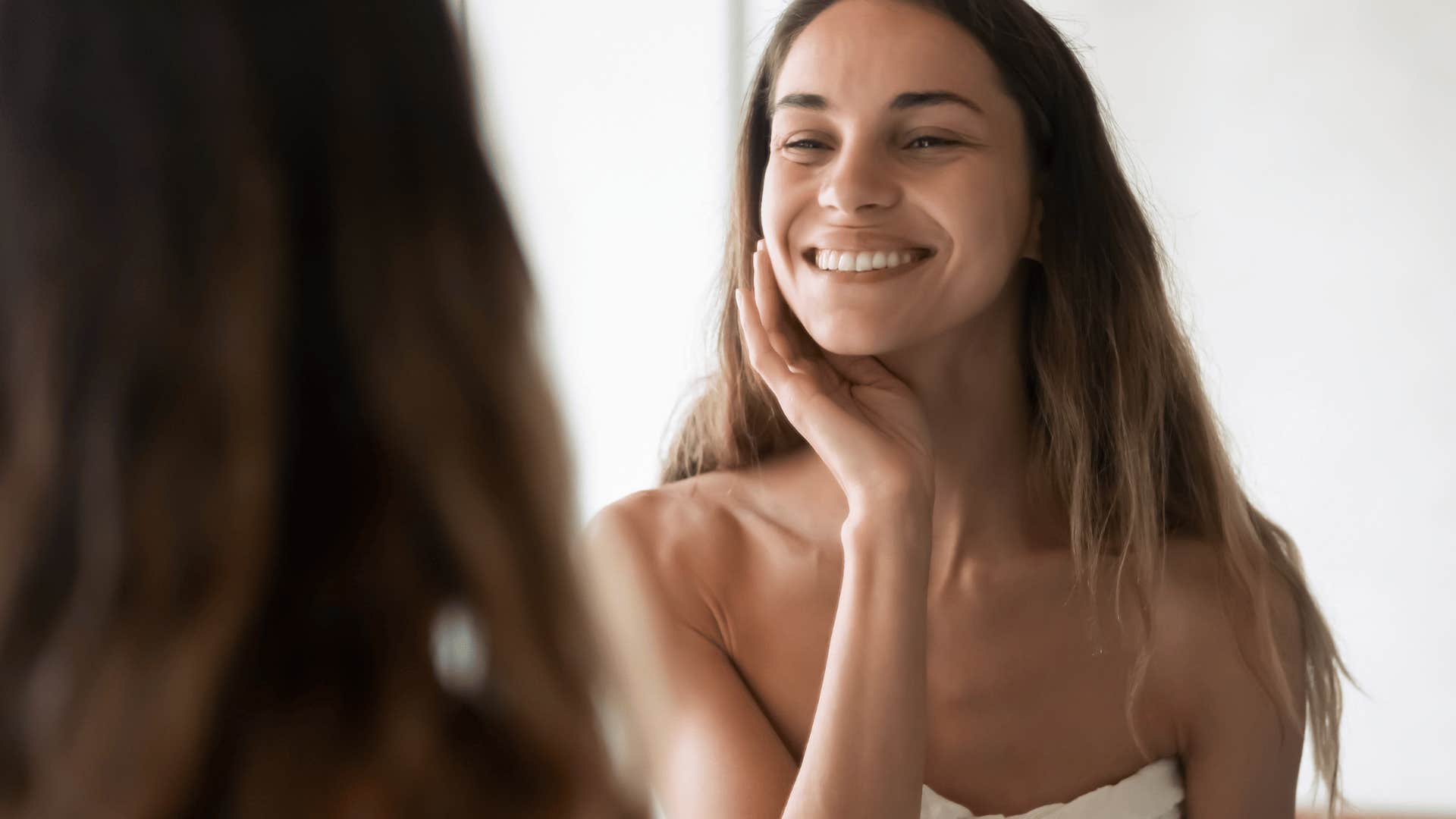 woman smiling and looking at herself in mirror