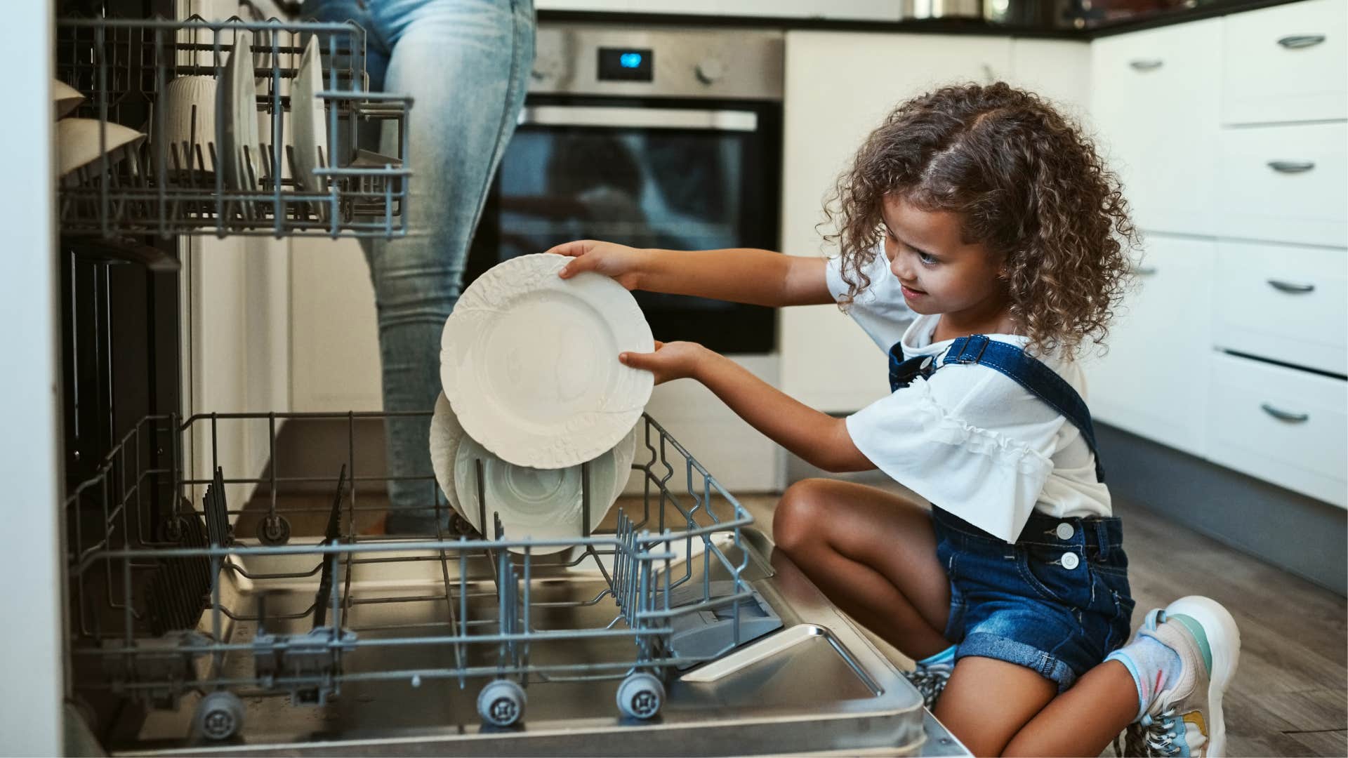 Young girl putting dishes in the dishwasher