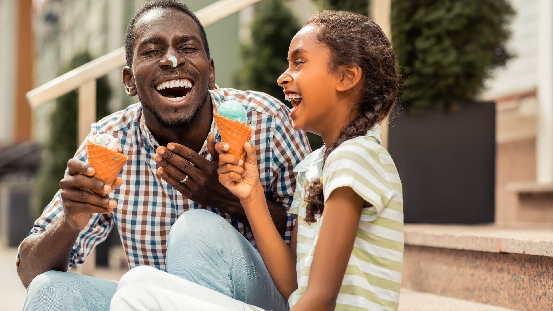 Man smiling and eating ice cream with his daughter