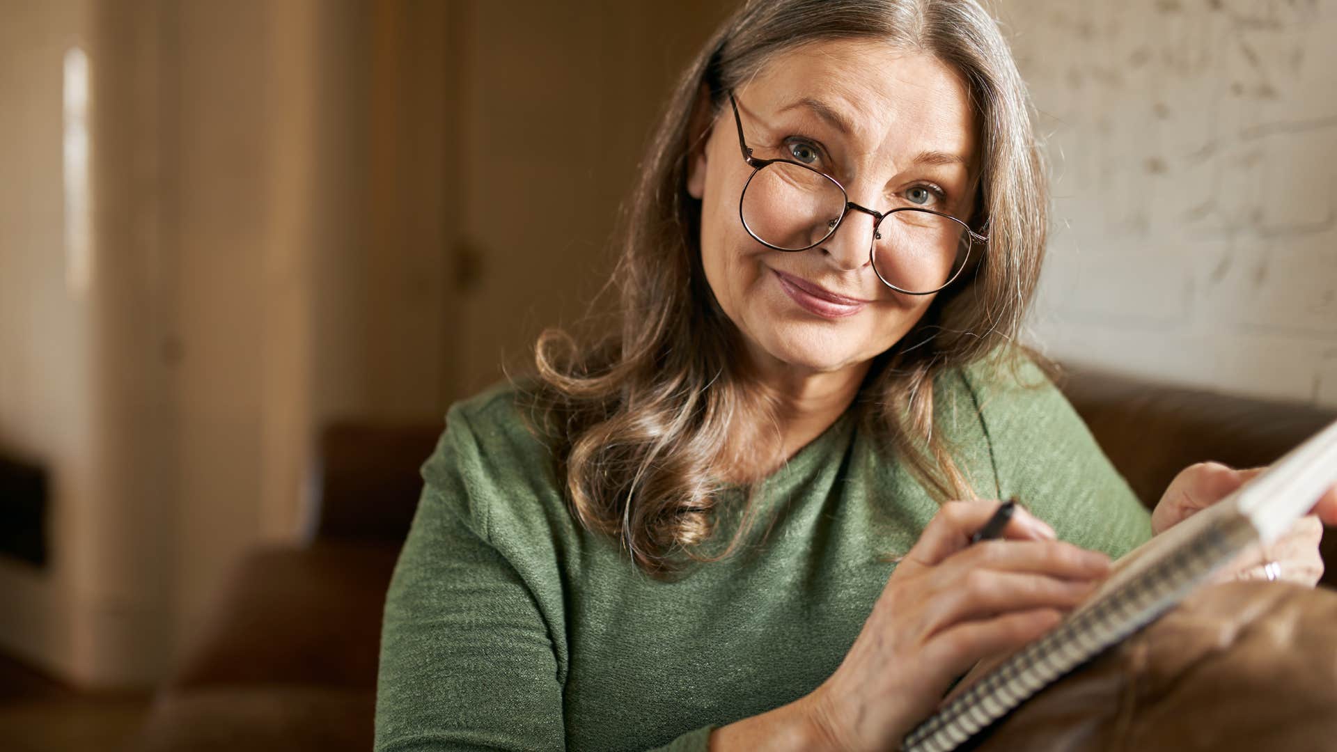 Older woman smiling and writing in her diary