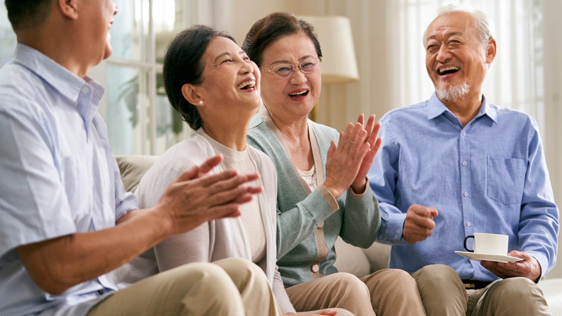 Two older couples laughing together in a living room