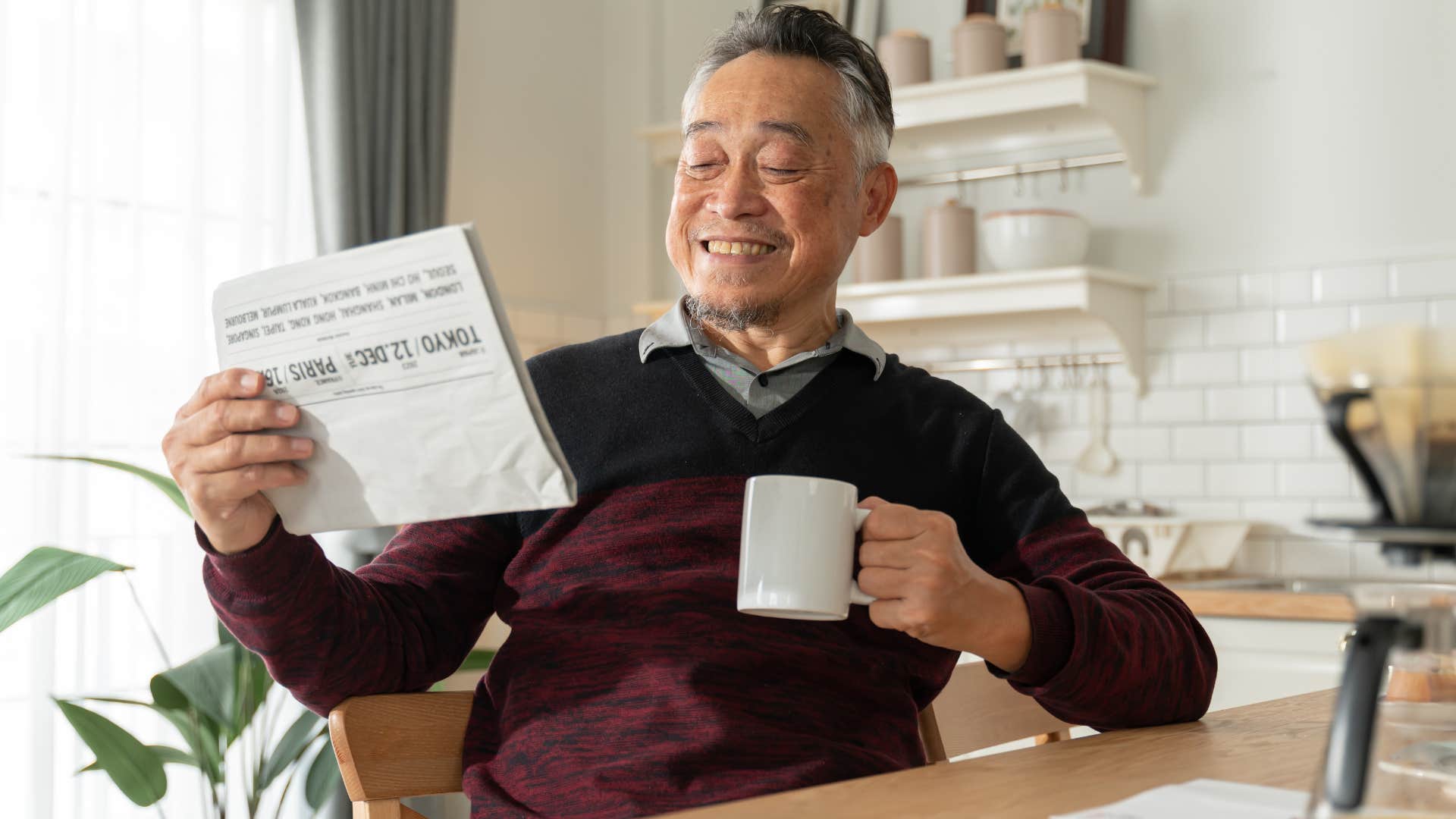 Old man drinking coffee and reading a newspaper