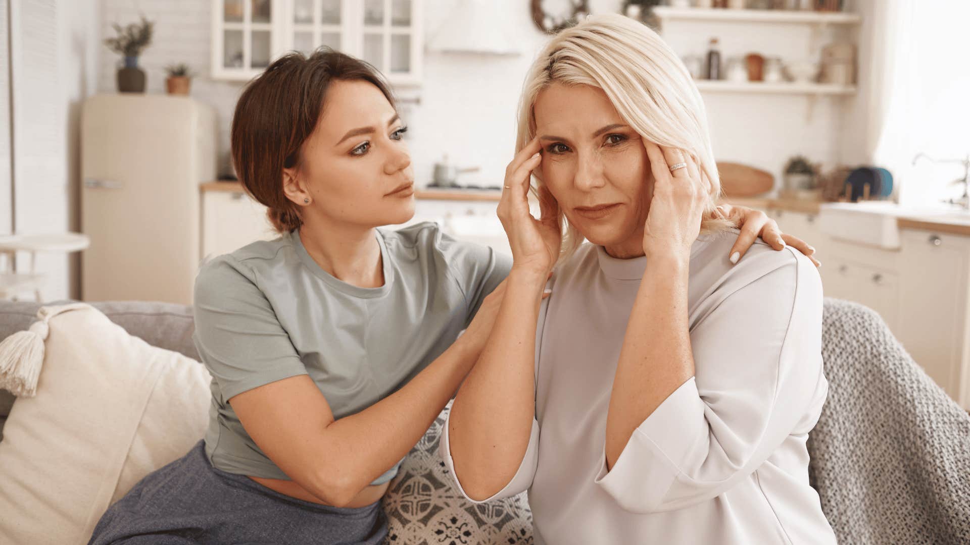 Older woman touches her head and gets compassion from younger woman