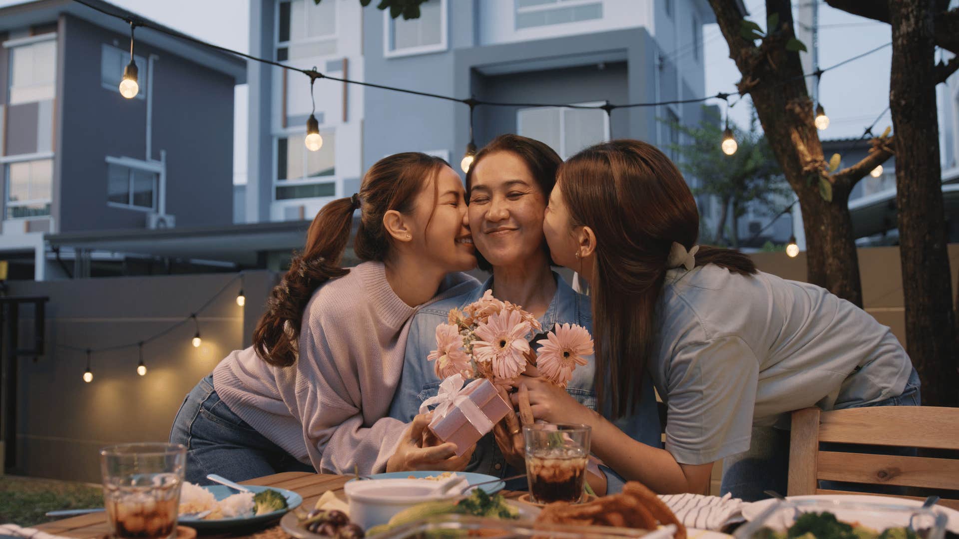 Daughter give gifts to mother and kiss her cheeks