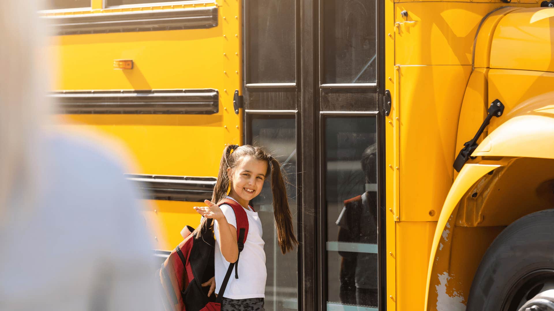 mother waving at daughter going on school bus