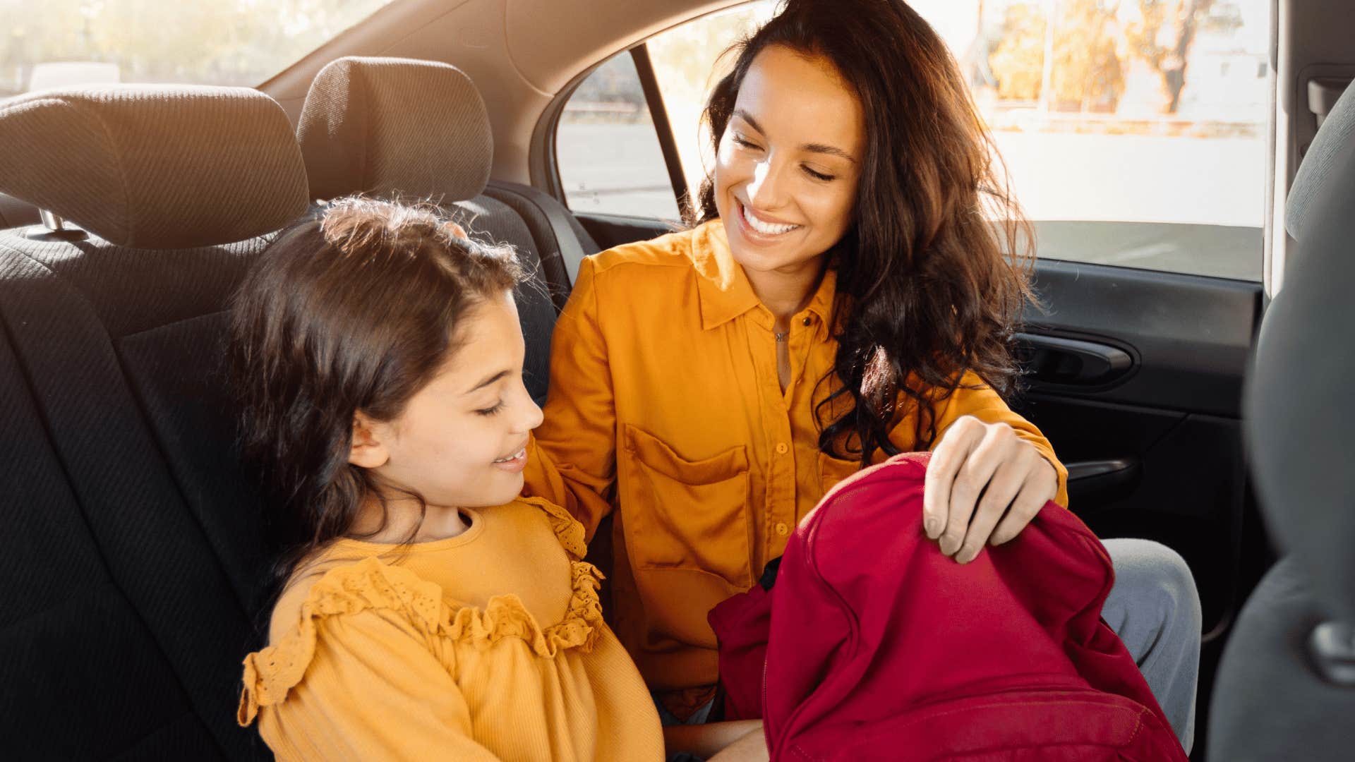 mom with child and backpack backseat car