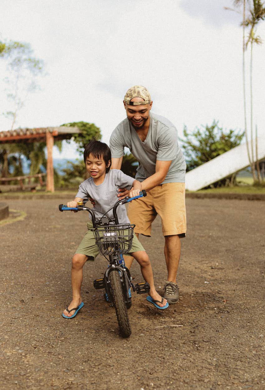 dad building trust with son by teaching him to ride a bike