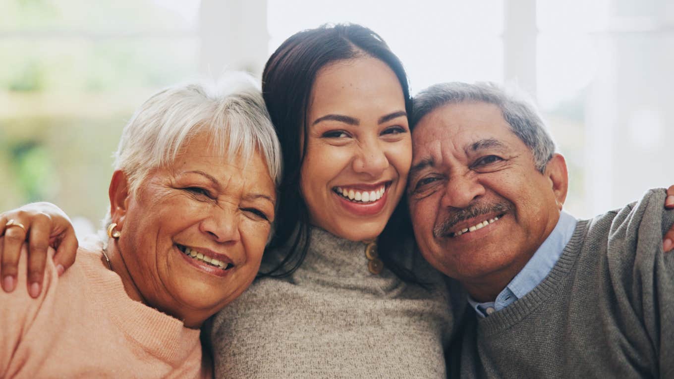 adult daughter lovingly hugging parents