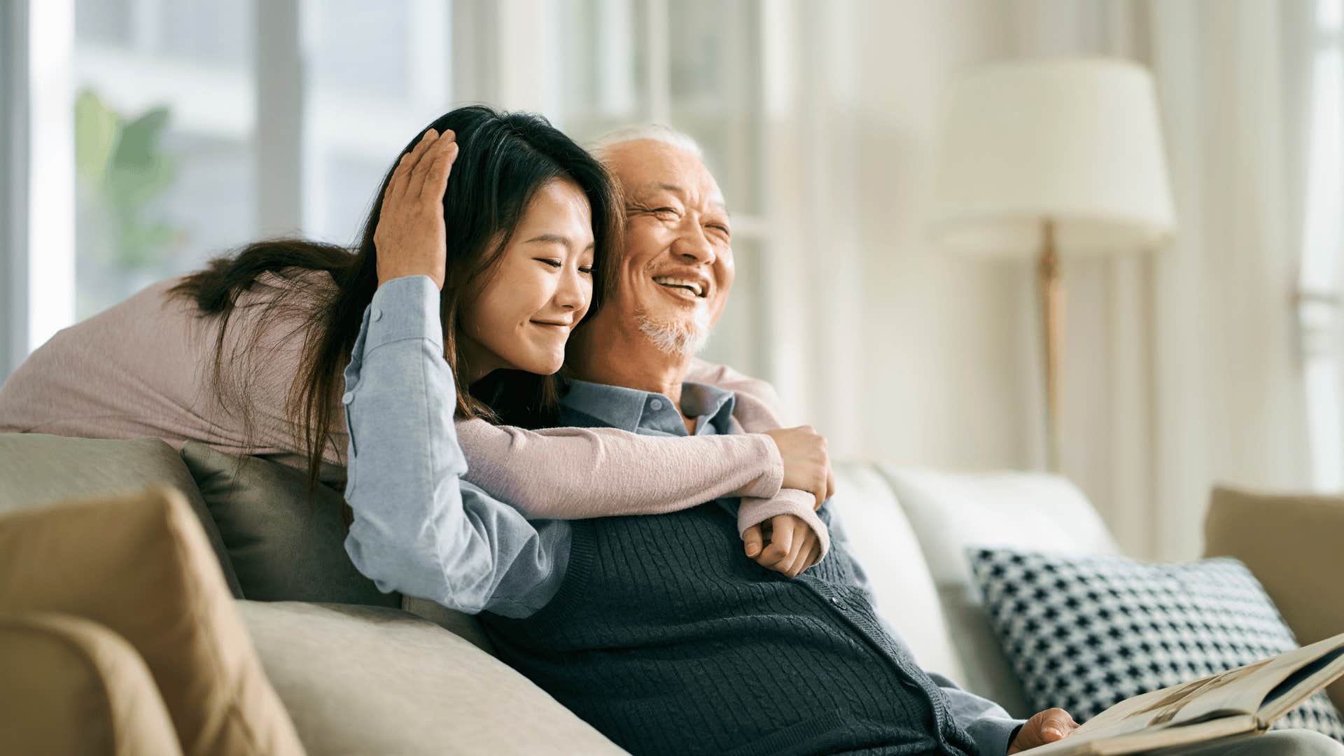 daughter hugging older father from behind seeking support