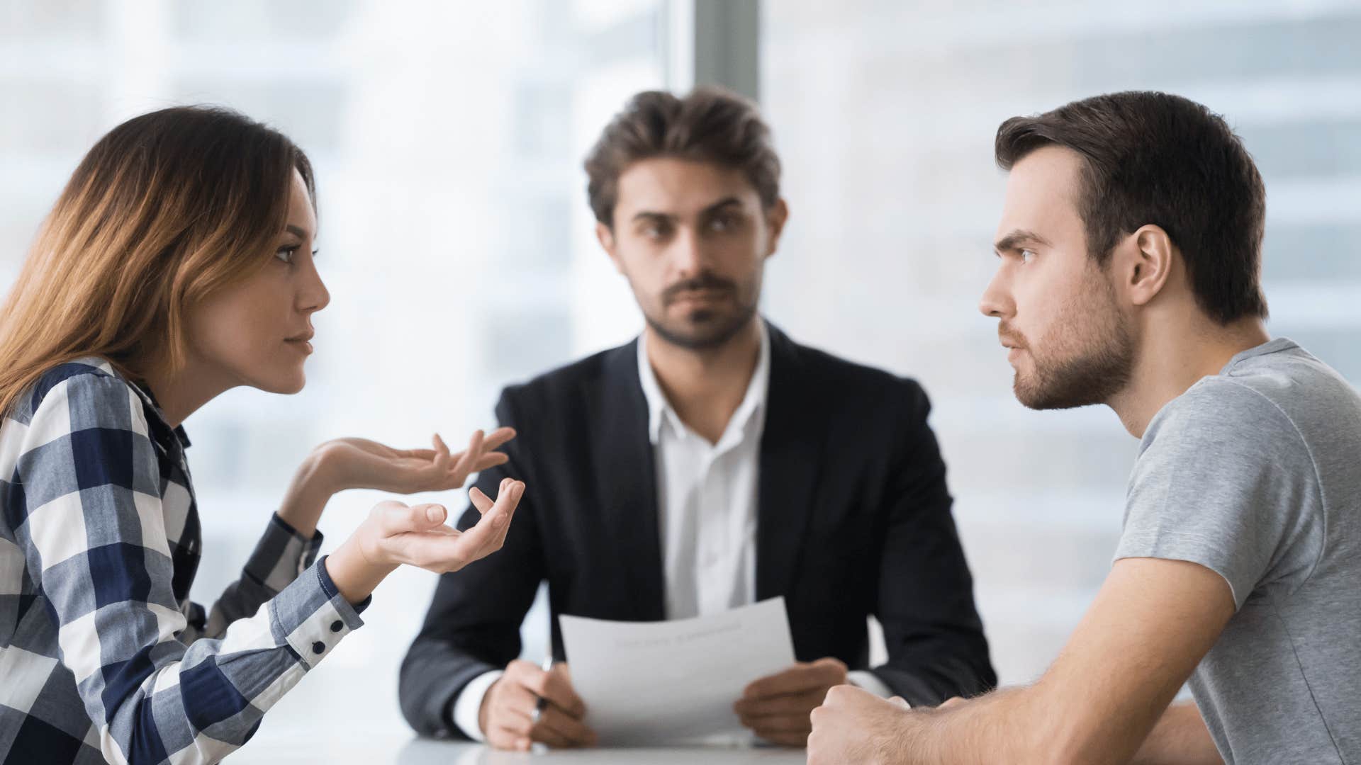 couple arguing in front of man at desk